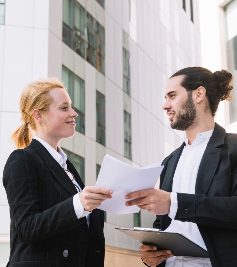 smiling-businessman-businesswoman-holding-paperwork-hands-outdoors (1)